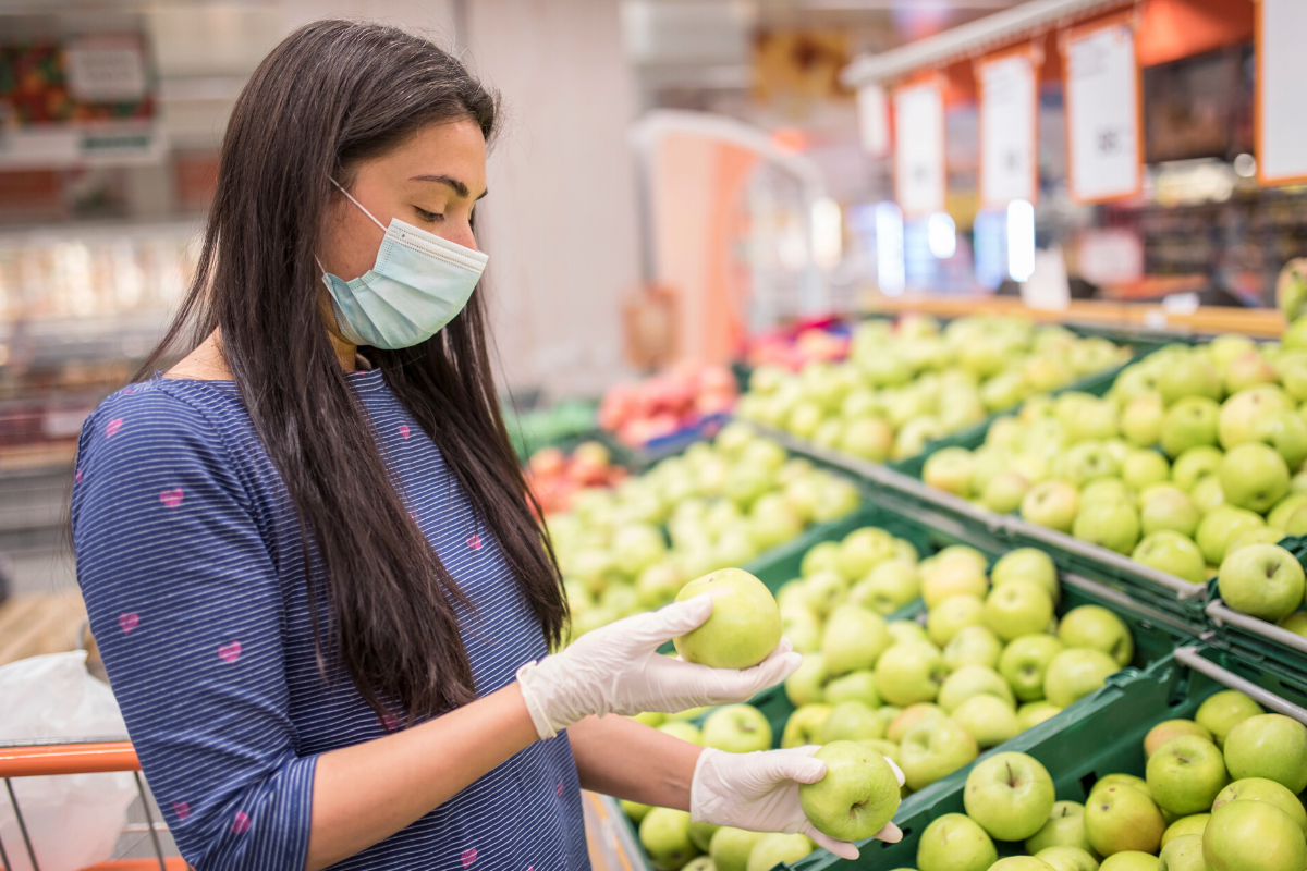 Woman Wearing a Mask in a Grocery Store Picking Apples